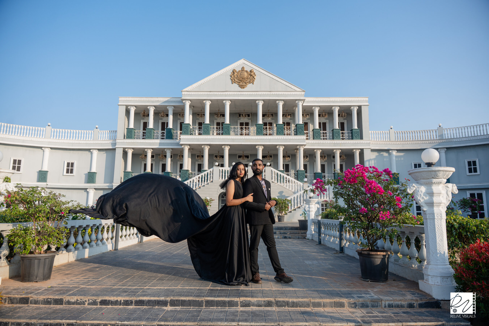A bride and groom posing in front of a grand architectural backdrop.