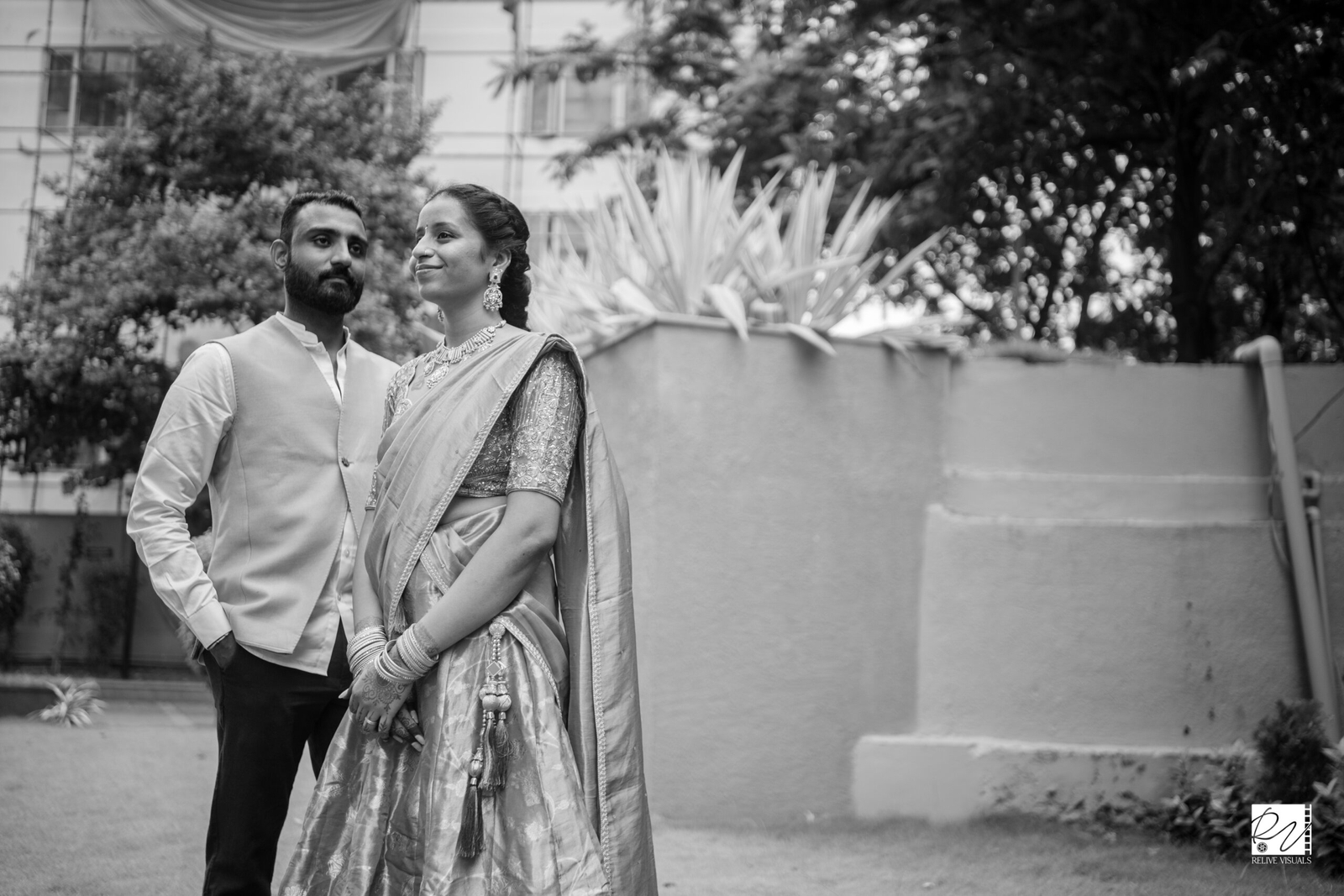 A couple in elegant attire, standing close and lost in the moment.