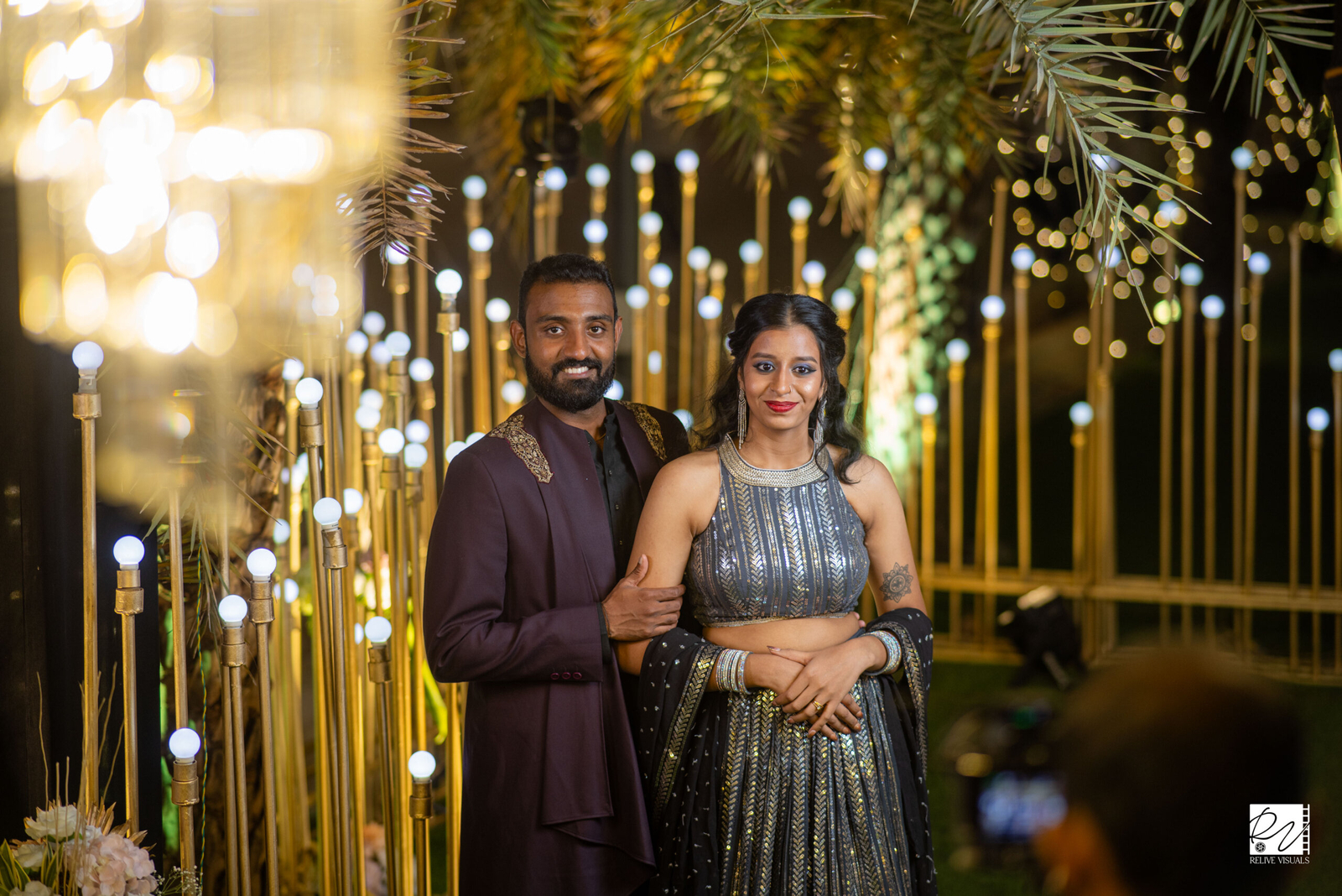 A couple standing side by side, holding hands and smiling softly.