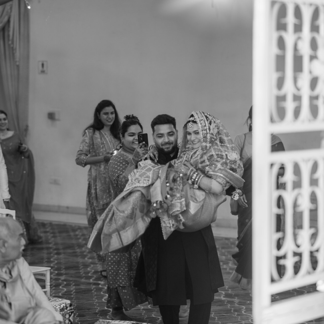 bride’s brother carries her playfully during the wedding ceremony, surrounded by laughter and joyful cheers.