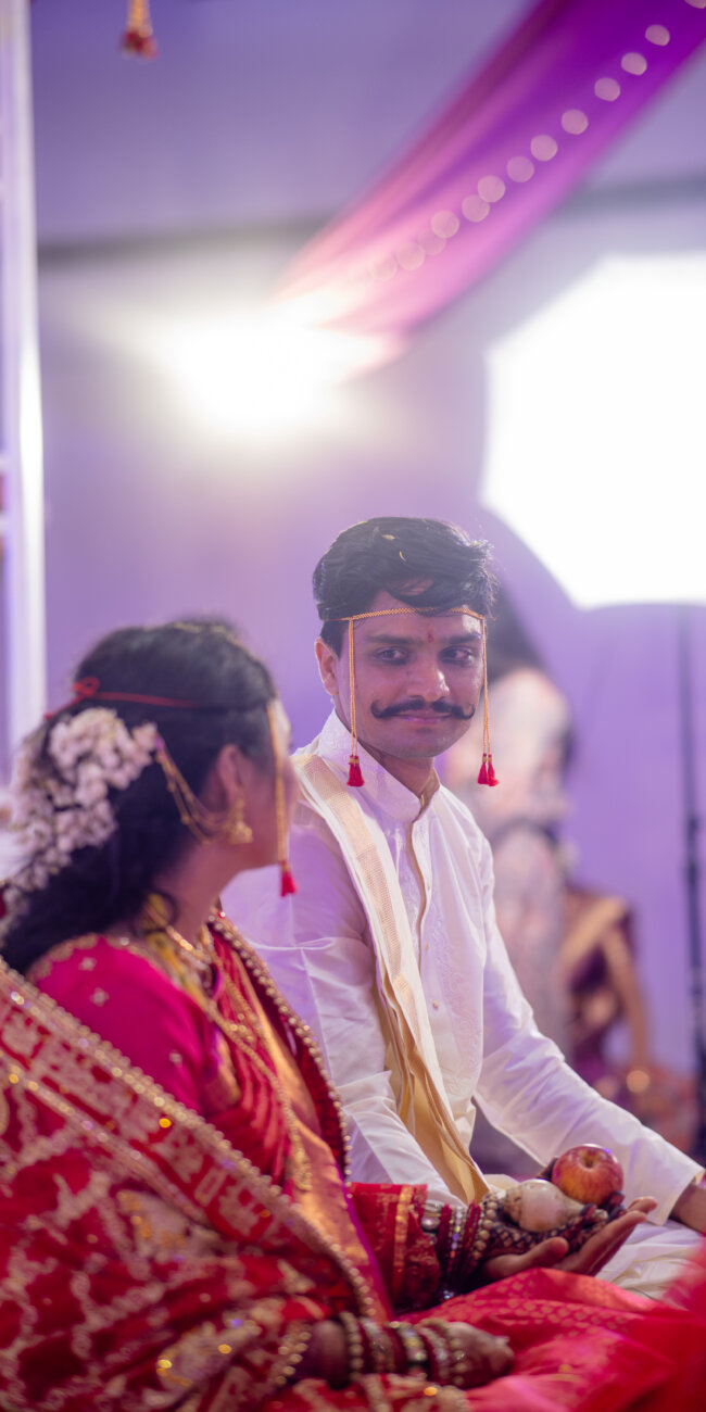 bride and groom stand facing each other, their eyes locked in a loving gaze, surrounded by wedding décor and soft light.