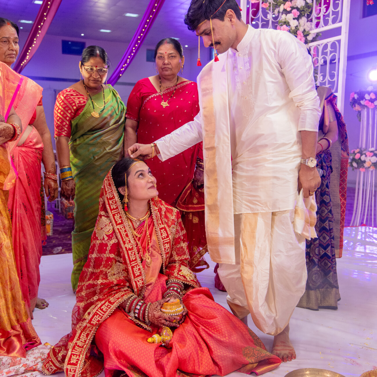 groom delicately applies sindoor to the bride’s maang, sealing their bond in a timeless wedding ritual.