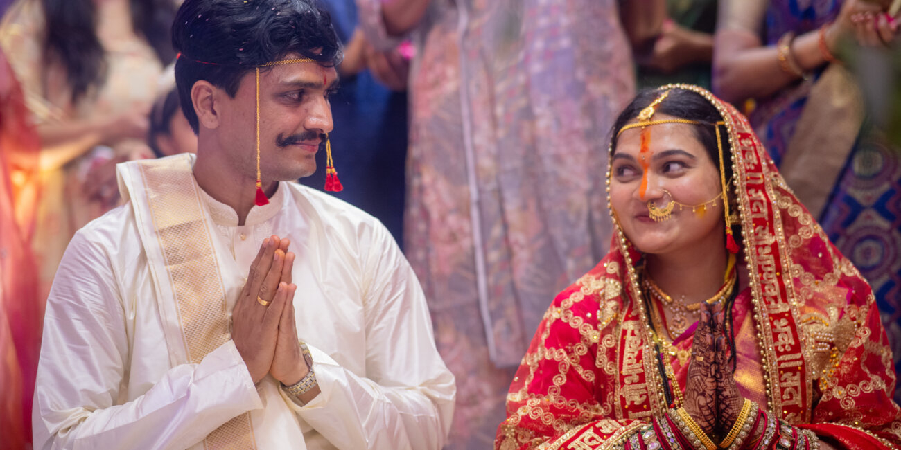 bride and groom bow respectfully in namaskaram to their elders, exchanging warm smiles and loving glances.
