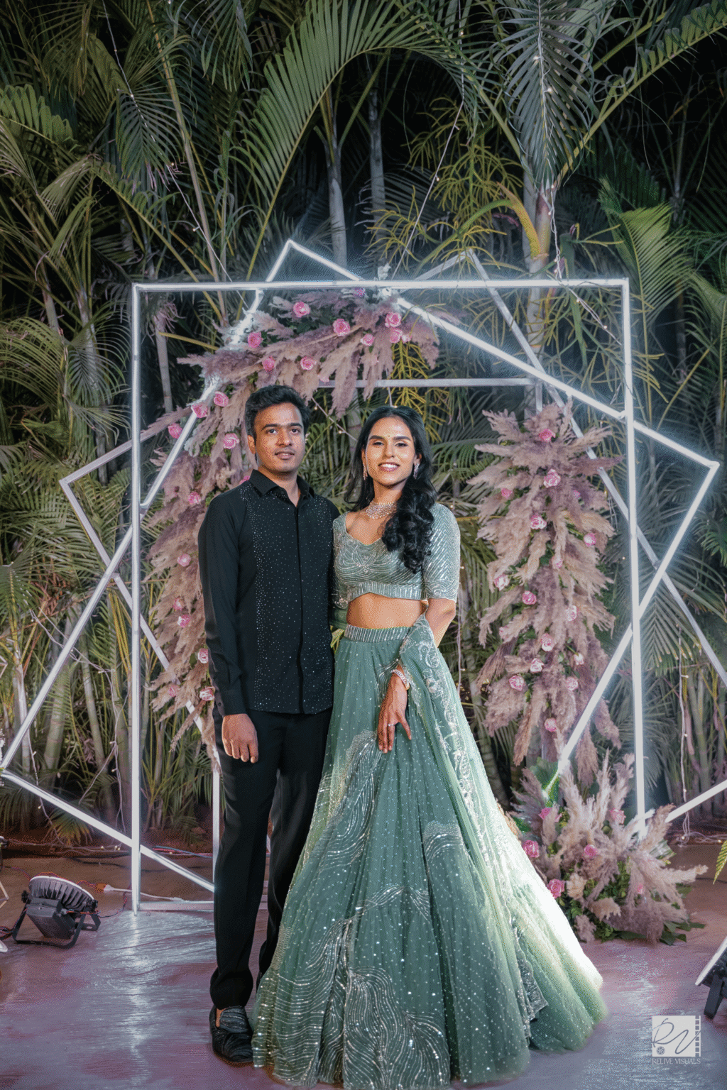 Couple standing together in front of elegant wedding decorations, smiling and posing for a photo.