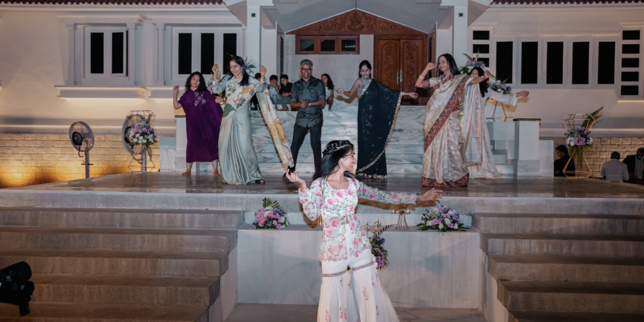 Energetic crowd dancing on stage with a girl leading the dance in the front.