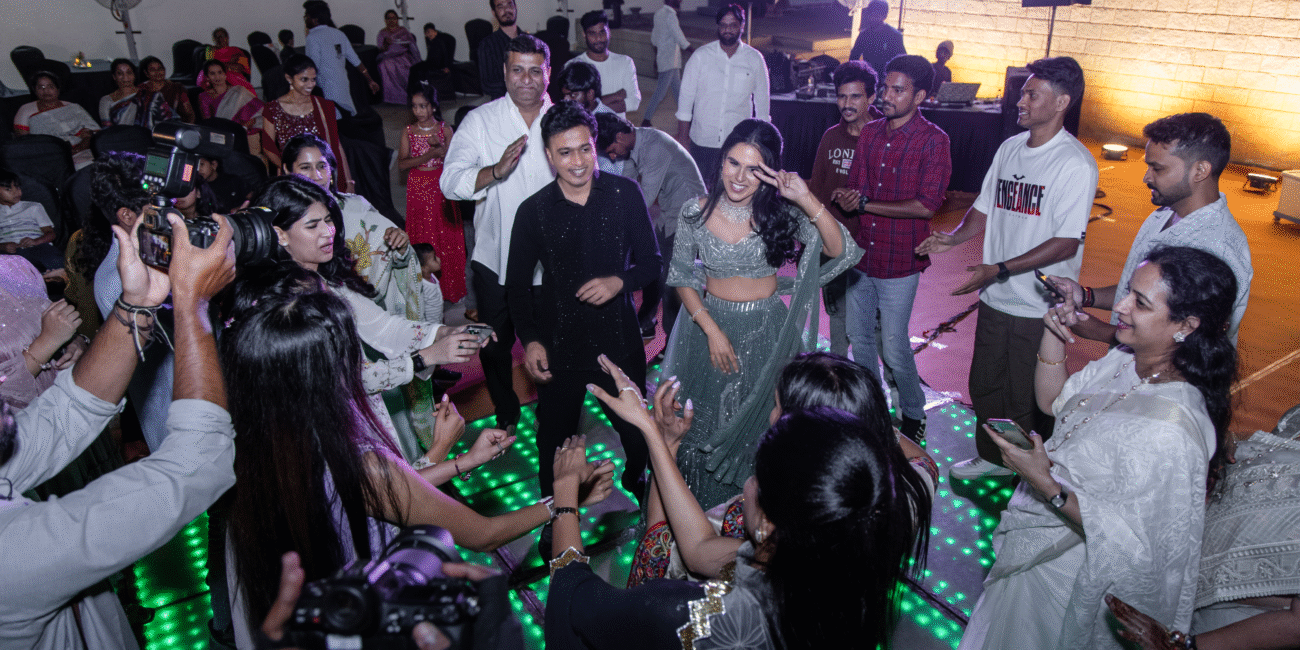 Couple dancing in the center of the dance floor, surrounded by a cheering and clapping crowd.