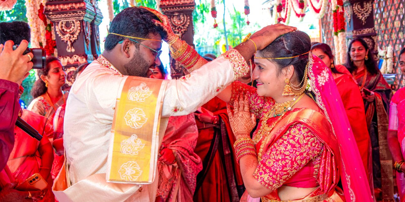 "Telugu bride and groom placing Jeelakarra Bellam on each other’s heads during the wedding ceremony"