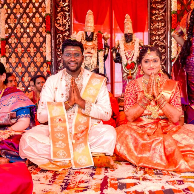 Telugu bride and groom seated together on the wedding stage in traditional attire, smiling and posing for guests and photos"