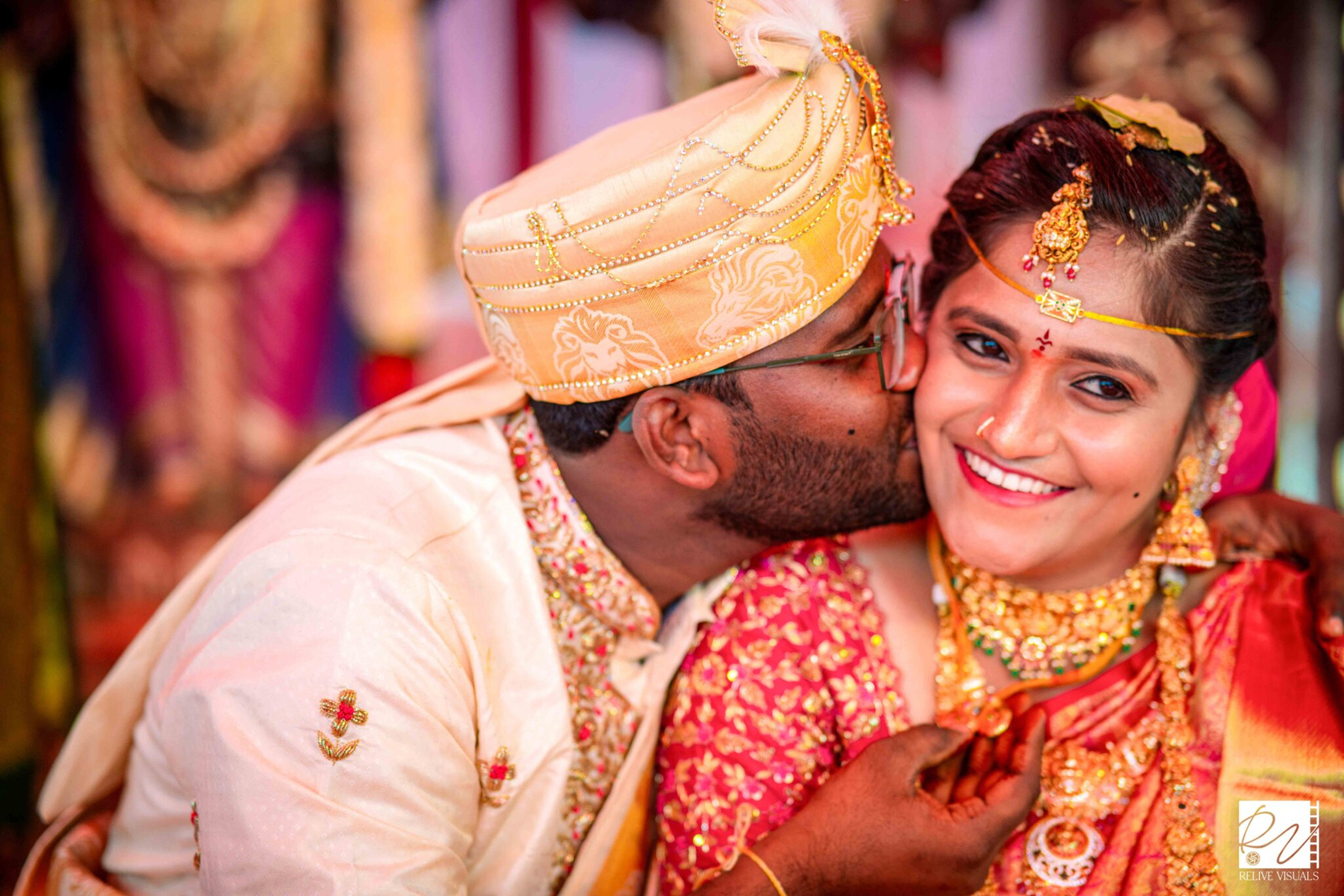 "Telugu groom gently kissing the bride on the checks while holding the Thali (Mangalsutra) during the wedding ceremony"