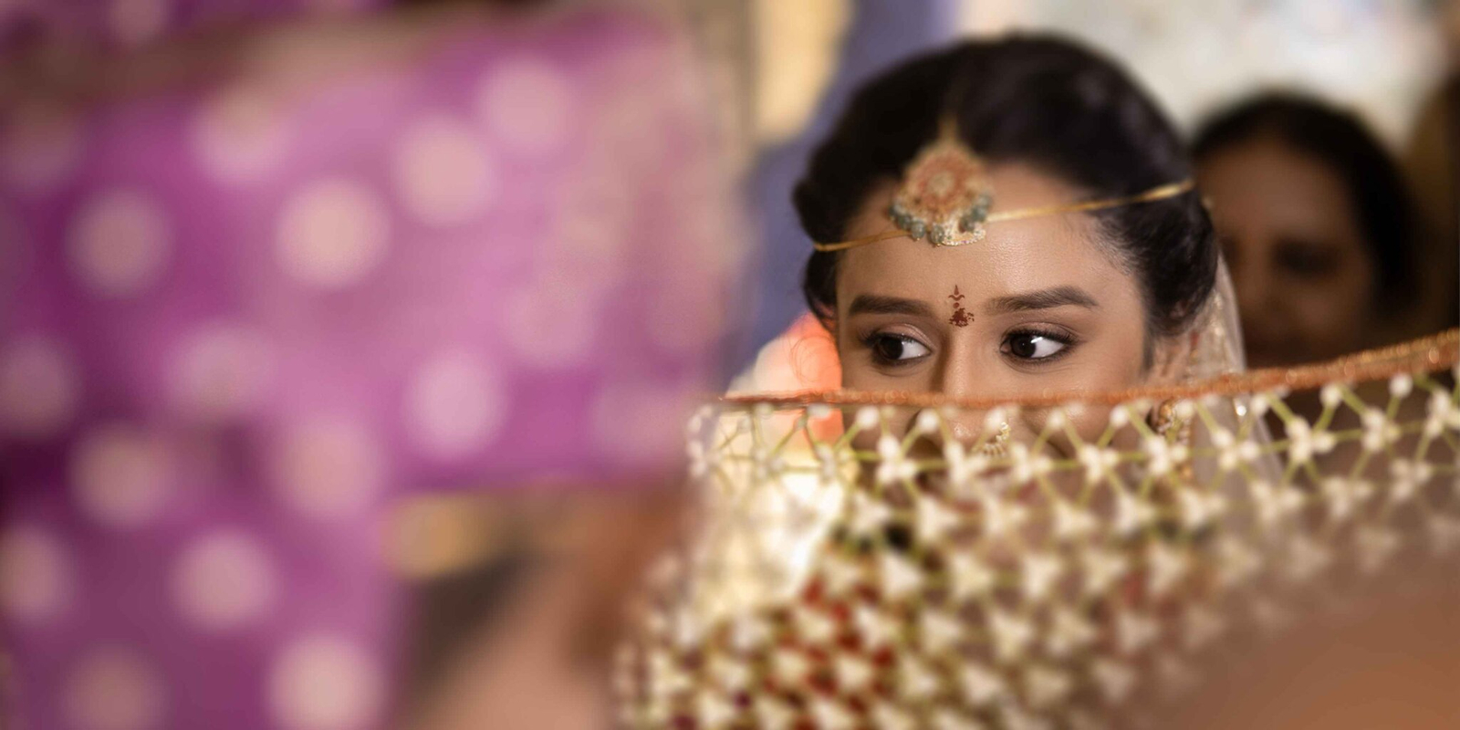 Close-up portrait focusing on the bride’s expressive eyes, framed by her wedding attire and jewelry.