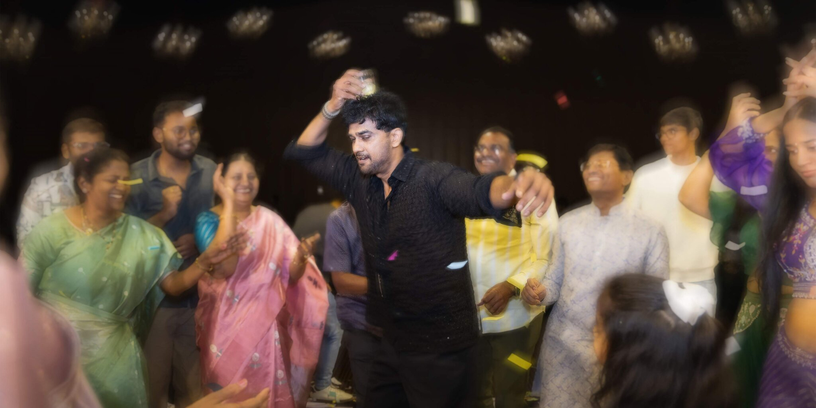 Group of friends balancing glasses on their heads, captured with a low shutter effect that creates a fun motion blur of lights.