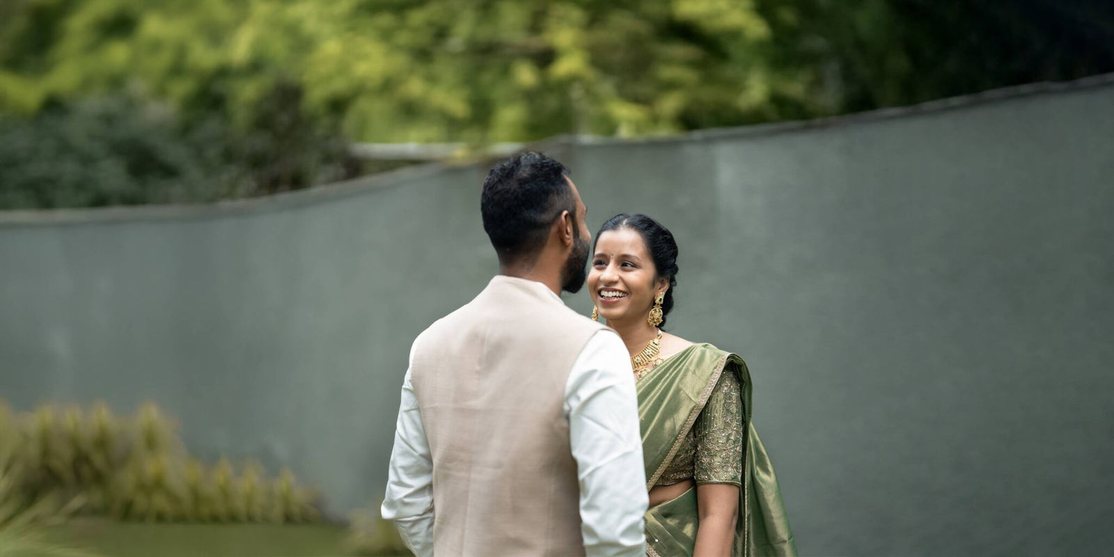 Wide-angle portrait of the groom gazing lovingly at the bride, set against a scenic and elegant backdrop.
