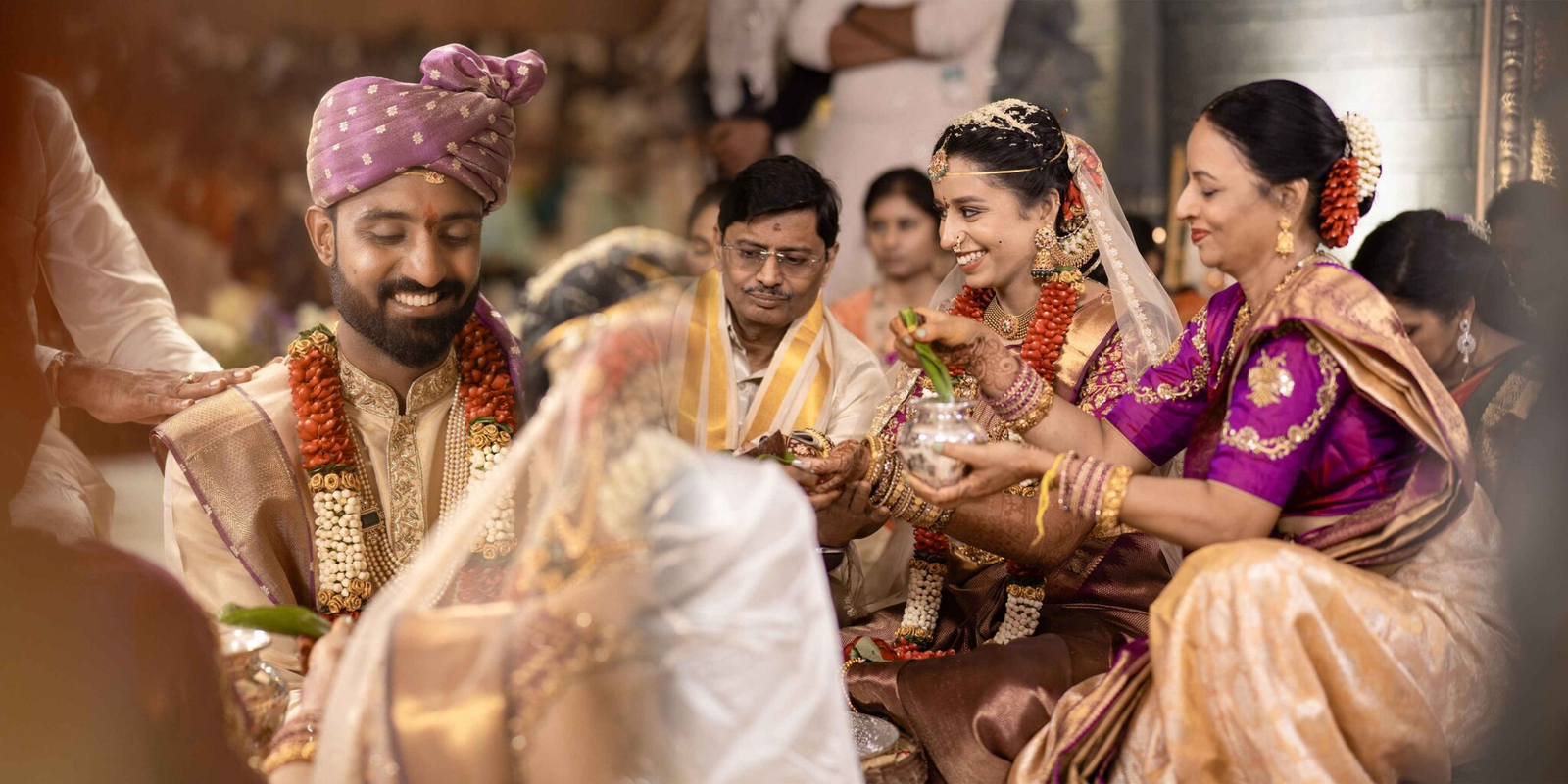 Bride and groom joined by the bride’s mother and father, performing a traditional pooja ritual together during the wedding ceremony.